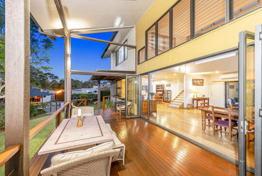 Outdoor dinning area show large glass sliding doors back into house